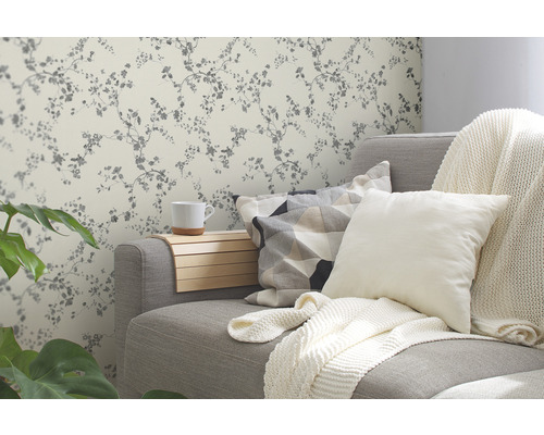 Obývacia izba so sivou pohovkou, vankúšmi a kvetinovou tapetou