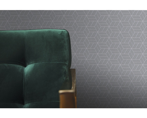 Detail šedej tapety s geometrickým vzorom a časť zelenej pohovky