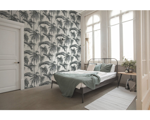 Spálňa s posteľou a tapetou s motívom paliem