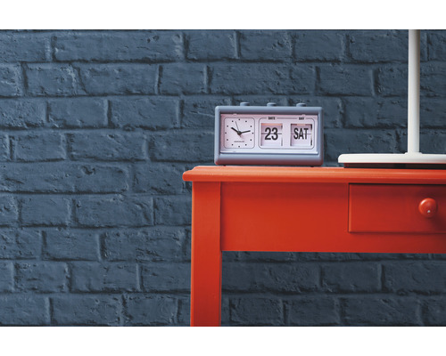 Stôl s preklápacím budíkom pred tehlovou stenou