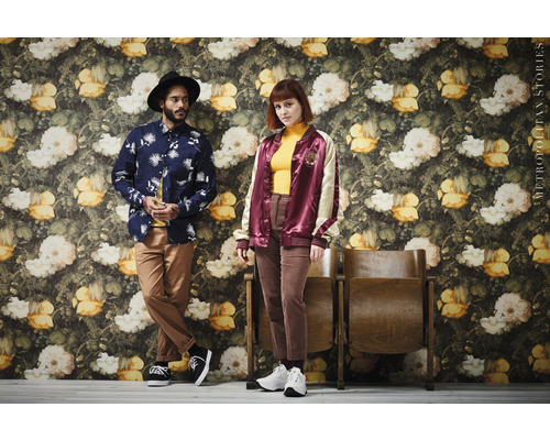 Dve osoby pózujú pred stenou s kvetinovým dekorom