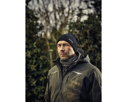 Muž s čiapkou, nákrčníkom a pracovnou bundou vonku