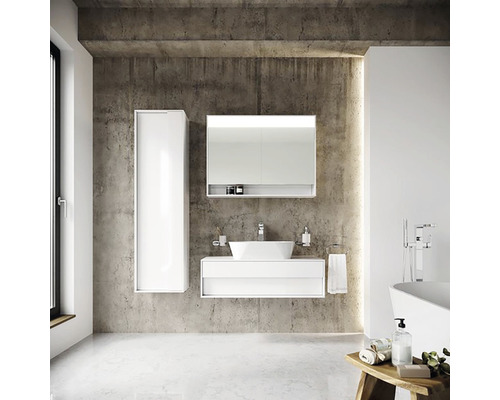 Moderná kúpeľňa s bielym umývadlom, zrkadlovou skrinkou a vysokou skriňou pred betónovou stenou