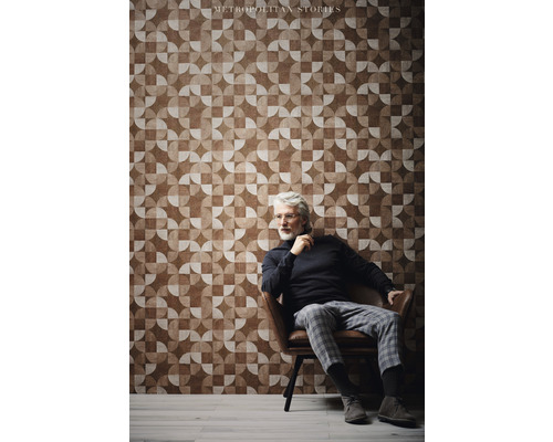 Muž sedí pred stenou s geometrickou tapetou z kolekcie Metropolitan Stories.