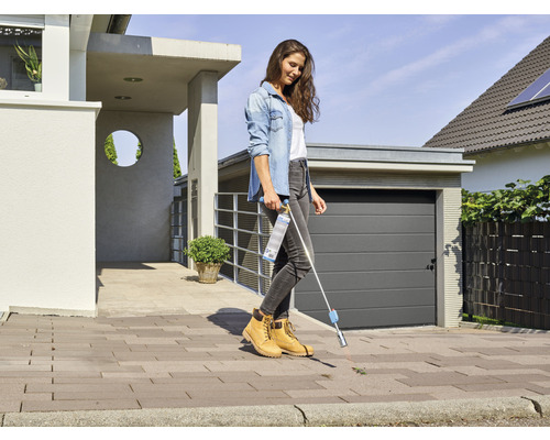 Žena odstraňuje burinu odstraňovačom buriny pred domom.