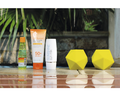 Opaľovací krém, opaľovacie mlieko a dva žlté dekoratívne objekty