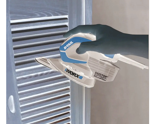 Ruka ovláda vibračnú brúsku značky Worx na drevenom povrchu.