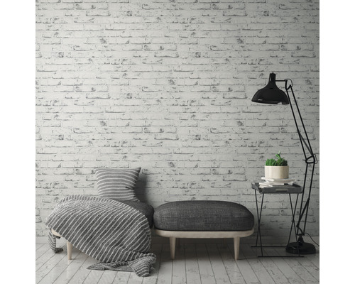 Dekoratívna obývacia izba s tapetou s tehlovým vzorom, posedením, stojacou lampou a odkladacím stolíkom.