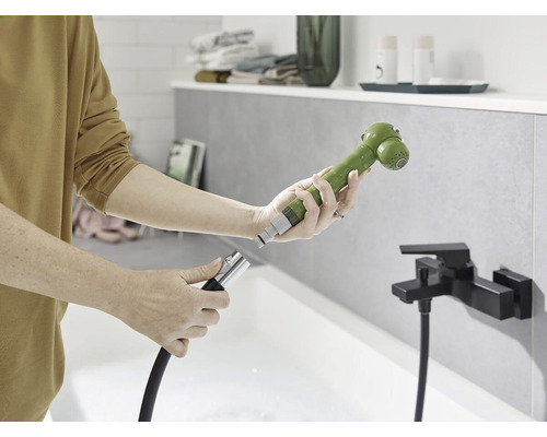 Osoba pripája sprchovú hlavicu k hadici v kúpeľni