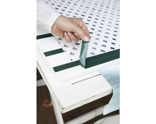 Osoba pripevňuje samolepiacu tesniacu pásku k plotovému prvku.