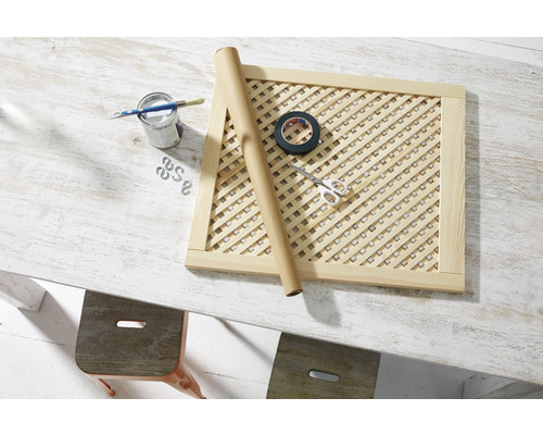 Drevený mriežkový rám s maliarskymi potrebami, lepiacou páskou a nožnicami na stole.