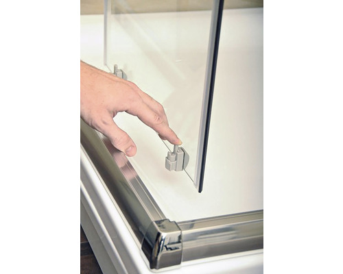 Detailný záber sklenenej sprchovej kabíny s rukou ovládajúcou upevňovací klip