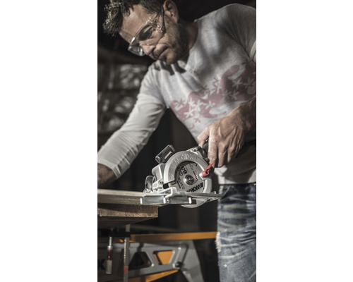 Muž pília drevenú dosku ručnou okružnou pílou Worx