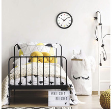 Detská izba s posteľou, nástennými hodinami a dekoratívnymi prvkami pre útulnú atmosféru.