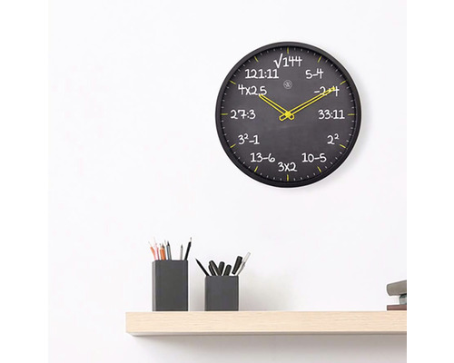 Nástenné hodiny s matematickými rovnicami na svetlej drevenej polici s držiakmi na perá