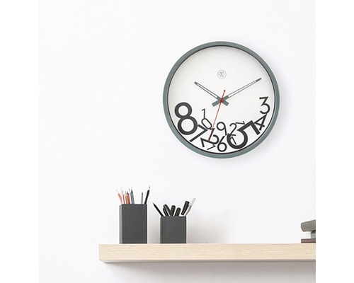 Nástenné hodiny so vzorom číslic nad policou s držiakmi na perá