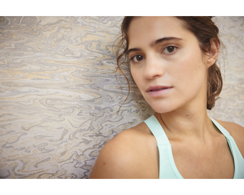 Žena pred tapetou s mramorovou štruktúrou