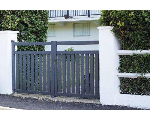 Sivá kovová záhradná bránka medzi dvoma bielymi stĺpmi