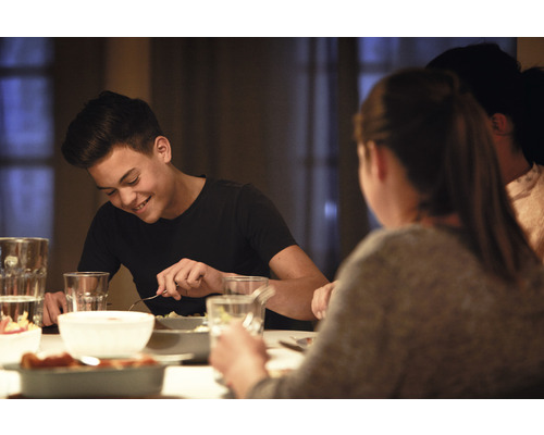 Scéna ľudí sediacich za jedálenským stolom a jedia