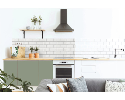 Moderná kuchyňa s bielymi metro dlaždicami, zelenými a bielymi skrinkami, digestorom a drevenými prvkami.
