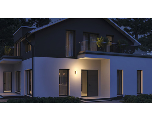 Osvetlený obytný dom s vonkajšou nástennou lampou v noci