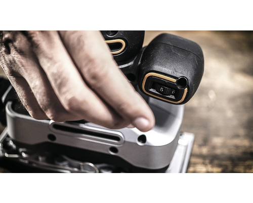 Detailný záber muža ovládajúceho vibračnú brúsku.