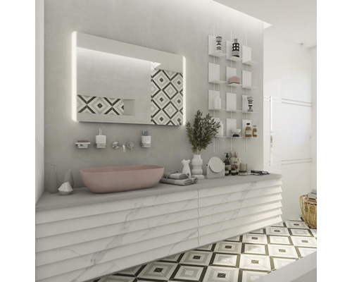 Svetlá kúpeľňa s umývadlom, osvetleným zrkadlom, nástennými policami a vzorovanou dlažbou.