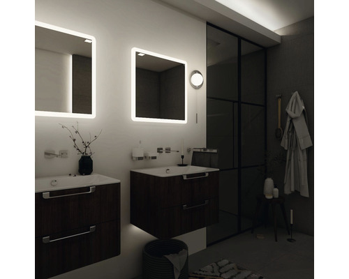 Kúpeľňa s umývadlami, osvetlenými zrkadlami a tmavým drevom