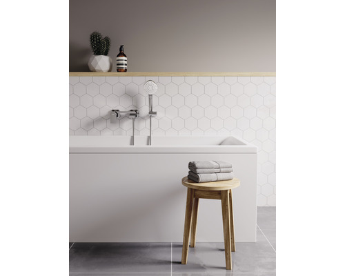 Svetlá kúpeľňa s vaňou, ručnou sprchou, uterákmi a drevenou stoličkou.