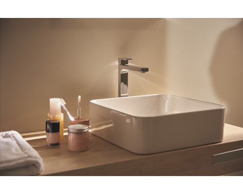 Umývadlo v kúpeľni s vodovodnou batériou a kozmetickými produktmi na drevenej polici