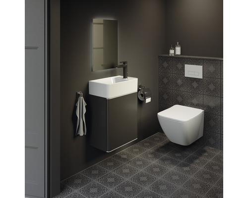 Moderná kúpeľňa s umývadlom, zrkadlom, toaletou a tmavými dlaždicami.