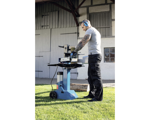 Osoba obsluhuje stojacu štiepačku dreva na trávniku