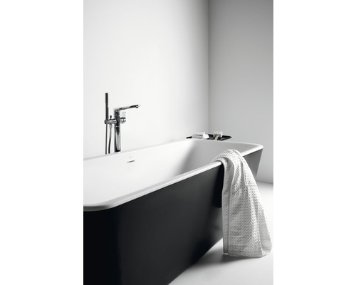 Voľne stojaca vaňa s batériou a uterákom v kúpeľni.