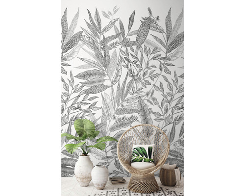 Obývacia izba s botanickou tapetou, prúteným kreslom a izbovou rastlinou