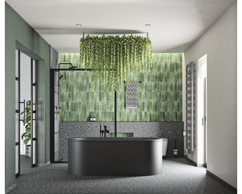 Moderná kúpeľňa s čiernou vaňou, zelenými obkladmi a visiacimi rastlinami pre svetlú a usporiadanú atmosféru.