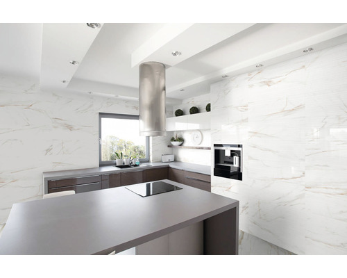 Moderná kuchyňa s kuchynským ostrovom, odsávačom pár a obkladom stien v mramorovom vzhľade.