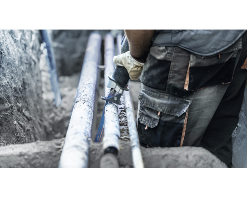 Remeselník reže potrubie mečovou pílou.