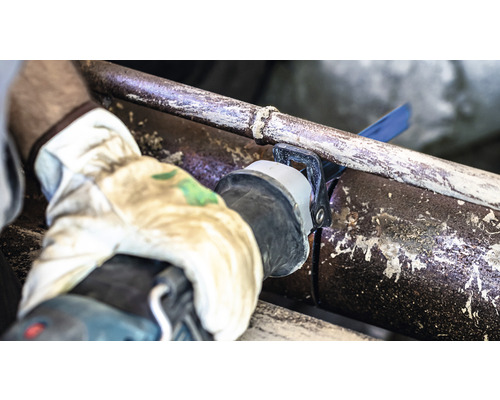 Osoba prerezáva rúru šabľovou pílou.