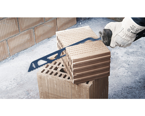 Muž pília pílou tehlu.