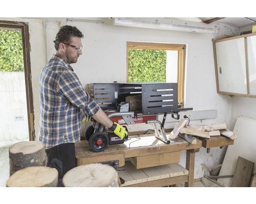 Muž obsluhuje štiepačku dreva na ponku a štiepe drevo.