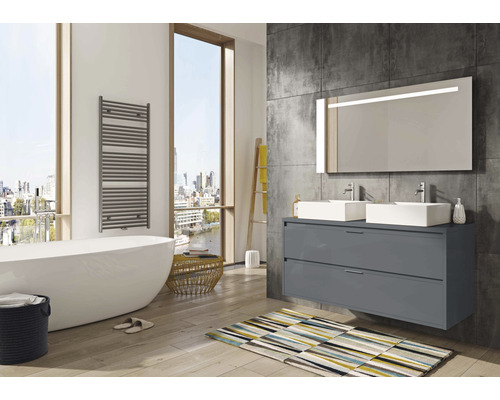 Kúpeľňa s vaňou, radiátorom na uteráky, umývadlovou skrinkou s dvomi umývadlami a osvetleným zrkadlom.