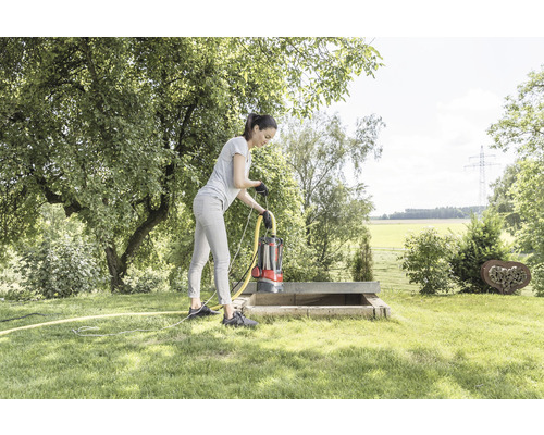 Žena obsluhuje ponorné čerpadlo v betónovej šachte v záhrade.
