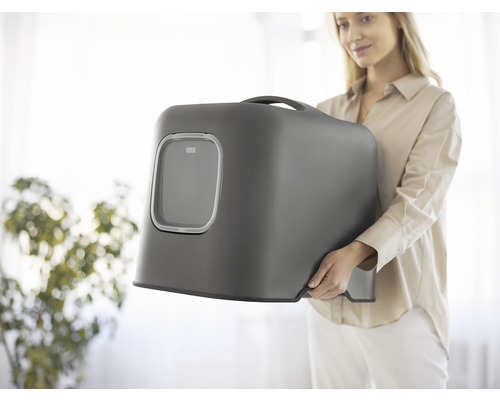 Žena nesie uzavretú mačaciu toaletu so vstupným otvorom