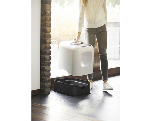 Žena nesie mačaciu toaletu s kapucňou a spodnou škrupinou