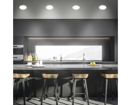 Moderná kuchyňa s kuchynským ostrovom, barovými stoličkami a stropnými bodovými svietidlami.