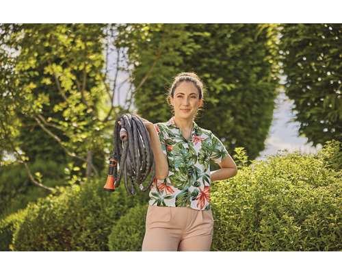 Žena drží záhradnú hadicu v záhrade