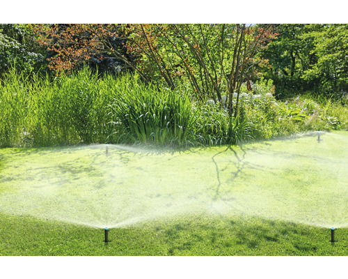 Zavlažovače zavlažujú zelený trávnik v záhrade.