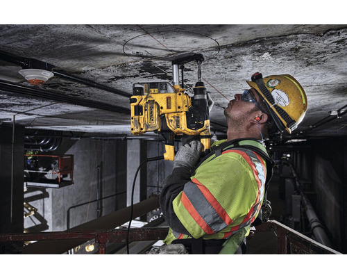 Stavebný robotník vŕta jadrovou vŕtačkou DeWalt otvor do betónového stropu.