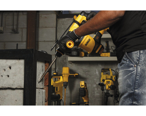 Muž používa búracie kladivo DeWalt na vŕtanie do tehlovej steny.