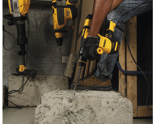 Remeselník používa búracie kladivo DeWalt na opracovanie betónu. V pozadí sú pripravené ďalšie vŕtacie kladivá.